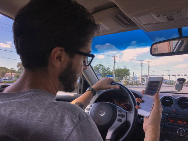 istock Man driving and looking his smartphone 1136858345