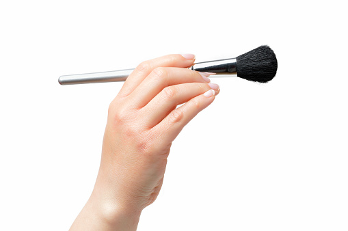 Cropped shot of an unrecognizable woman hand using a makeup brush isolated on a white background