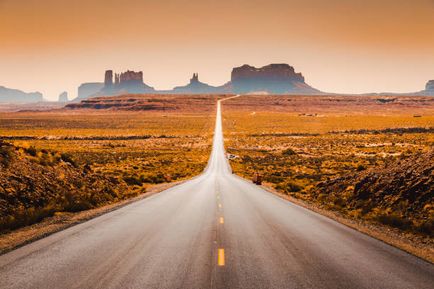 Classic panorama view of historic U.S. Route 163 running through famous Monument Valley in beautiful golden evening light at sunset in summer, Utah, USA