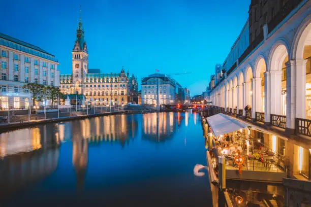 Classic twilight view of Hamburg city center with historic town hall reflecting in Binnenalster during blue hour at dusk, Germany