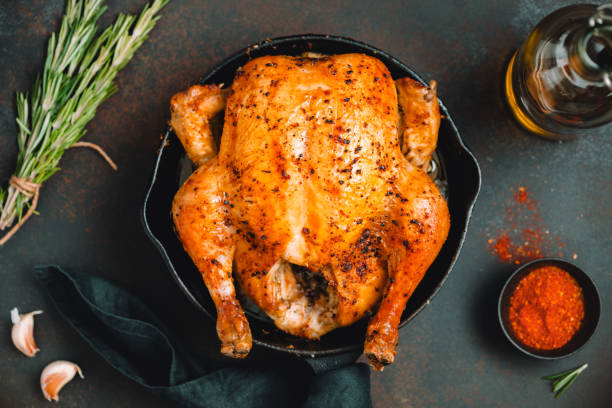 istock Roasted whole chicken with spices in a black iron skillet on a table. 1136861312