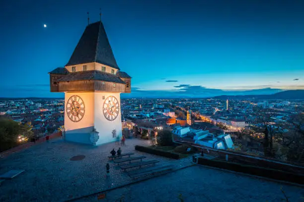 Beautiful twilight view of famous Grazer Uhrturm (clock tower) illuminated during blue hour at dusk, Graz, Styria region, Austria
