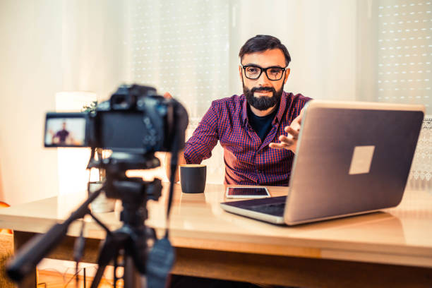 Man sitting at the desk in front of the camera making video.