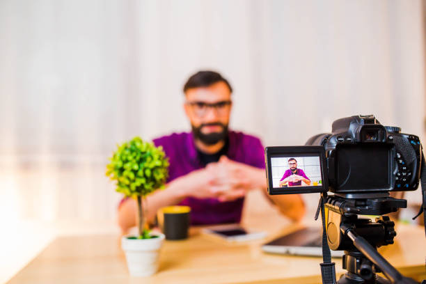istock Man sitting at the desk in front of the camera making video. 1136864210