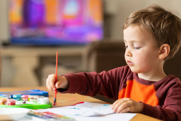 Three years old child painting with watercolors