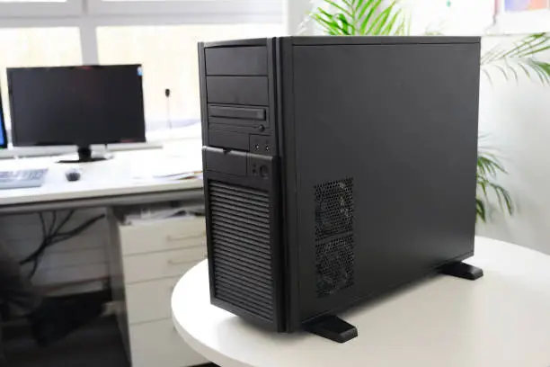 black server computer in a tower case on a white table in the office, selected focus