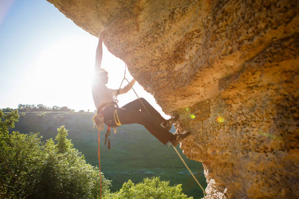 istock Image of man climber in helmet clambering up cliff. 1136869065