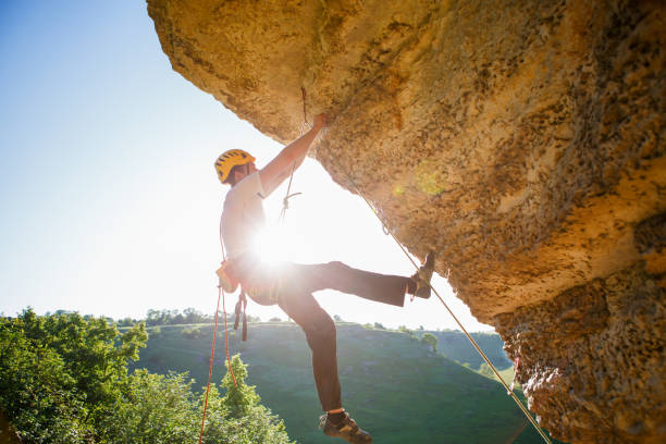 istock Image of man climber in helmet clambering up cliff. 1136869078