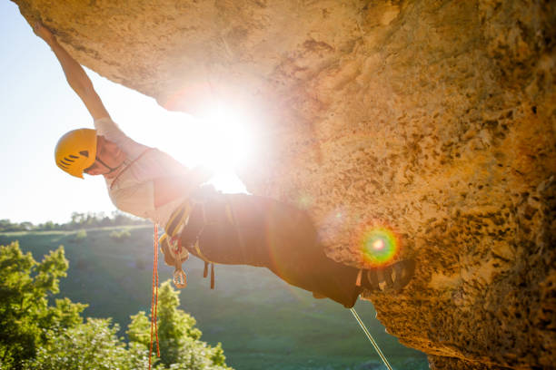 istock Image of man climber in helmet clambering up cliff. 1136869104