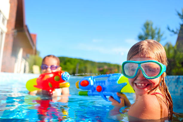 プールで水の銃で遊んで面白い小さな女の子 - water toy ストックフォトと画像