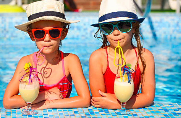 two happy little girls in sunglasses with cocktails wearing hats - child party group of people little girls imagens e fotografias de stock