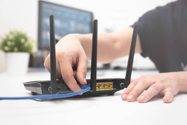 istock Man connects the internet cable to the router 1136871697