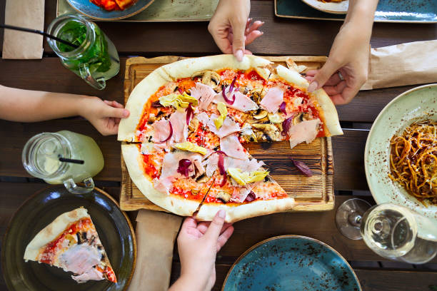 Concept of friendly family dinner party preparation. Horizontal, dinner with pizza, pasta, white wine and lemonade