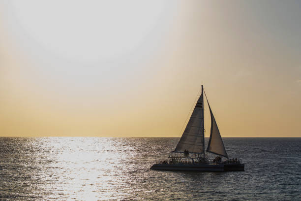 Sunset over Cozumel Sun setting with sailboat on Caribbean Sea off San Miguel Cozumel. san miguel de cozumel stock pictures, royalty-free photos & images