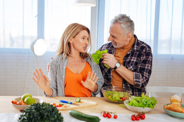 husband calming his overemotional wife while cooking salad - overemotional imagens e fotografias de stock