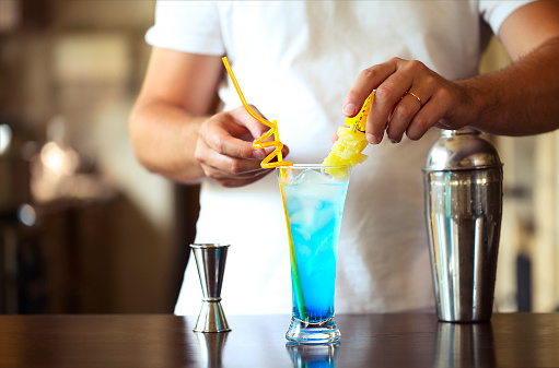 Barman at work, preparing cocktails. Pouring blue lagoon cocktail glass. Service and beverages concept