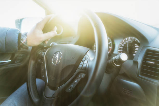 Closeup of a Acura (RDX 2017) car steering wheel. Lots of sunlight around. Acura Canada. One hand on the steering wheel. Driving a car.