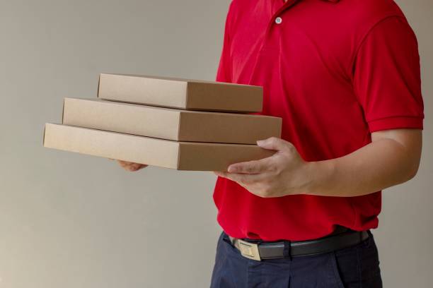 istock Delivery man standing with parcel post box on brown background. 1136883240
