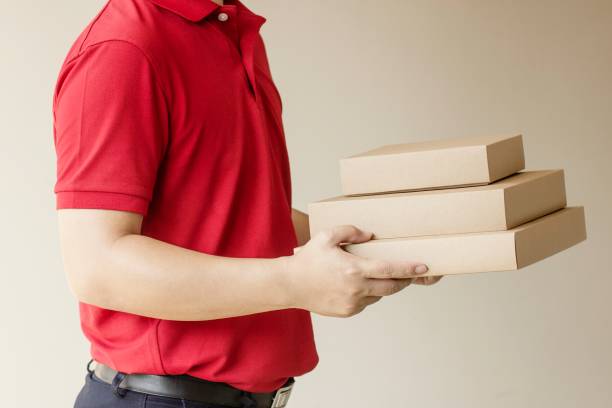 istock Delivery man standing with parcel post box on brown background. 1136883485