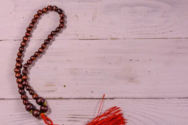 Photo of Brown rosary on the white wooden table. Top view