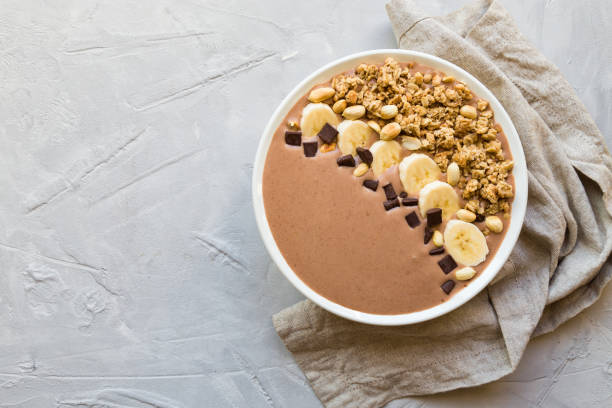 istock Chocolate smoothie bowl with bananas, granola and peanuts on light gray concrete background 1136884954