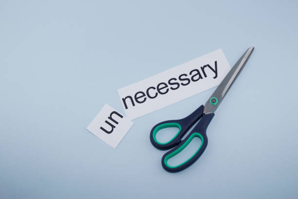istock necessary and unnecessary.Hand cutting paper with scissors 1136885074