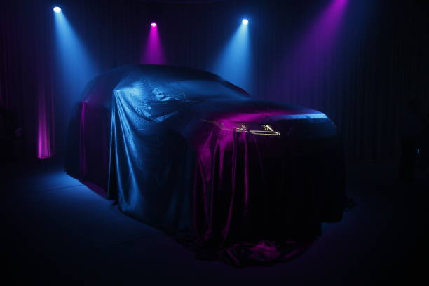 Car covered with dark cloth on a black background stock photo