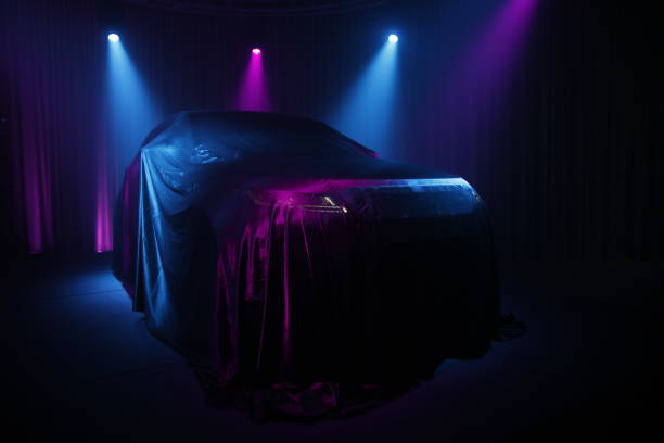 istock Car covered with dark cloth on a black background 1136889023