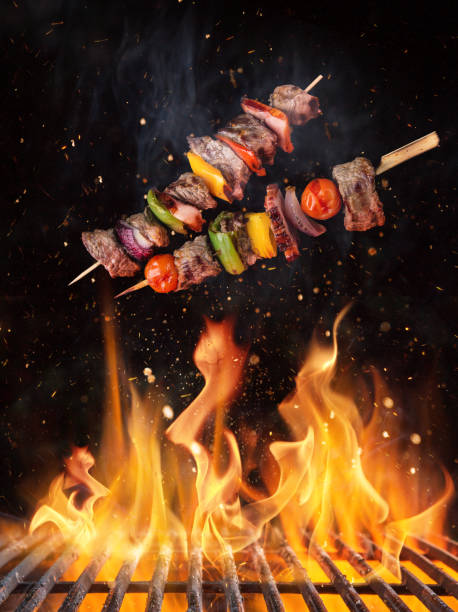 istock Tasty skewers flying above cast iron grate with fire flames. 1136889178