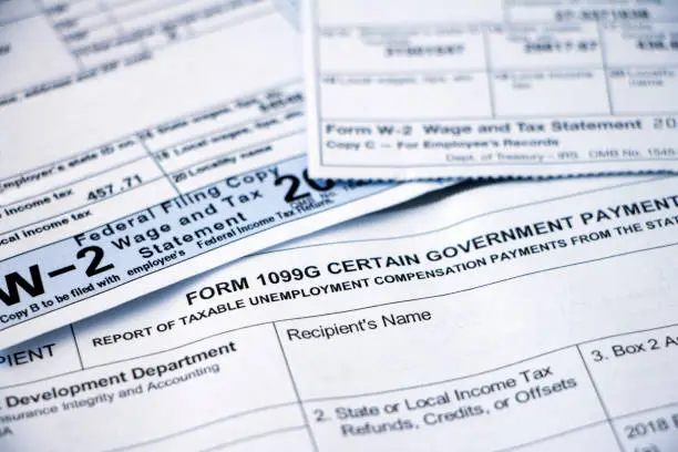 Closeup of overlapping Form 1099G Certain Government Payouts and W-2 forms.