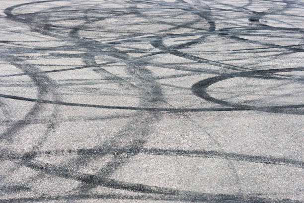 piste de voiture avec des traces de dérive en caoutchouc. texture de fond d'asphalte de chaussée. - tire track skidding asphalt tire photos et images de collection