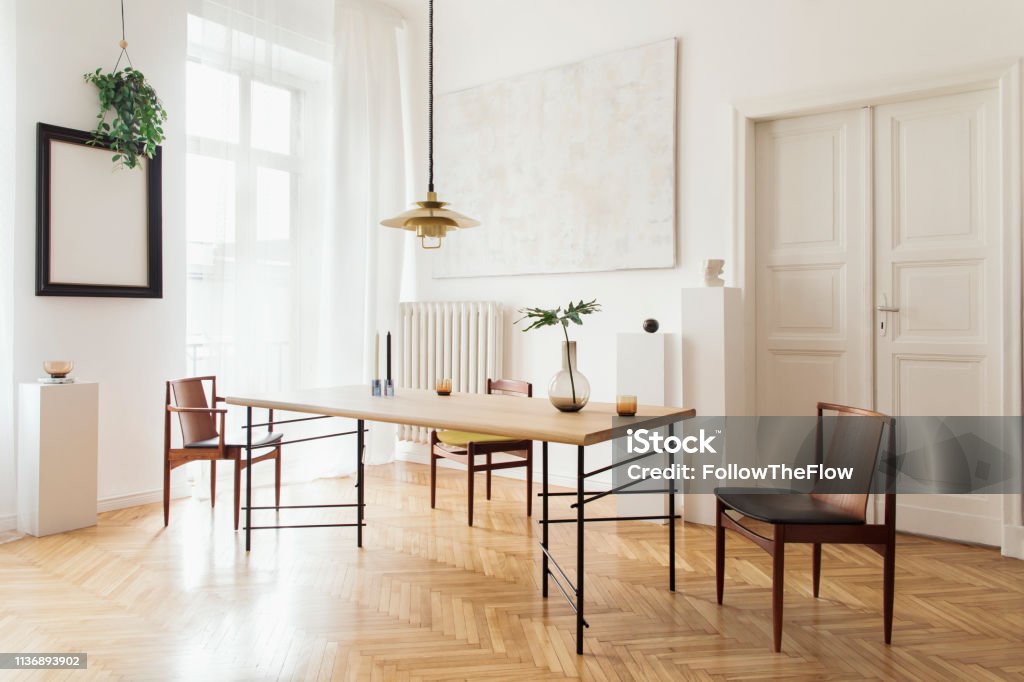 Stylish And Modern Dining Room Interior With Design Sharing Table Chairs Gold Pedant Lamp Abstract Paintings And Elegant Accessories Tropical Leafs In Vase Eclectic Decor Brown Wooden Parquet Stock Photo - Download Stylish And Modern Dining Room Interior With Design Sharing Table Chairs Gold Pedant Lamp Abstract Paintings And Elegant Accessories Tropical Leafs In Vase Eclectic Decor Brown Wooden Parquet Stock Photo - Download