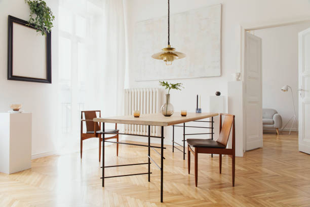 istock Eclectic and elegant dining room interior with design sharing table, chairs, gold pedant lamp, abstract paintings and stylish accessories. View to living room. Eclectic decor. Brown wooden parquet. 1136894446