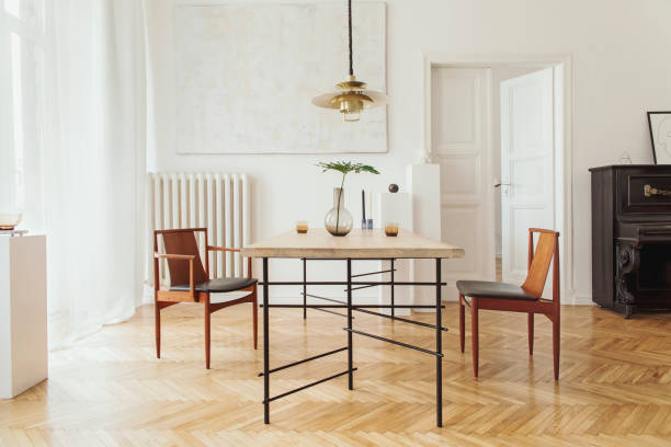istock Eclectic and elegant dining room interior with design sharing table, chairs, gold pedant lamp, abstract paintings, piano and stylish accessories. Eclectic decor. Brown wooden parquet. Real photo. 1136894453
