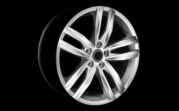 Aluminium modern car wheel rim in dramatic light at night. Vehicle rim isolated on black background.