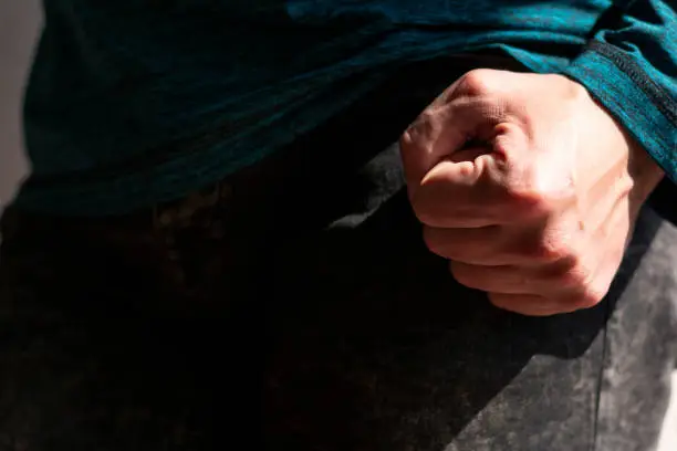 Close up view of Caucasian man's fist under strong natural sunlight with the rest of the body in shadow