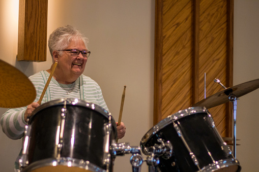 this bright color image features a senior woman playing the drums