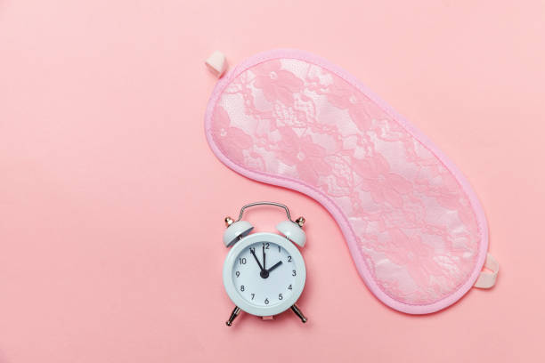 istock Sleeping mask and alarm clock on pink pastel background 1136902034