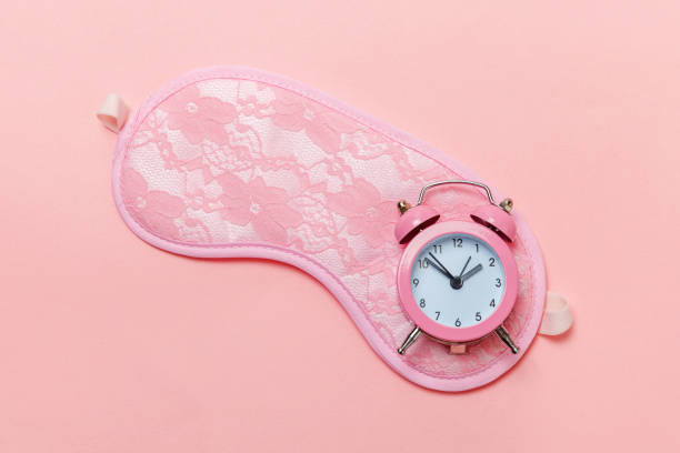 istock Sleeping mask and alarm clock on pink pastel background 1136902078