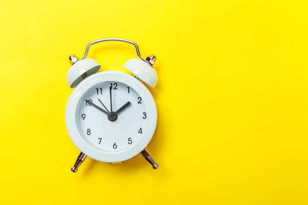 istock Vintage alarm clock Isolated on yellow background 1136902717