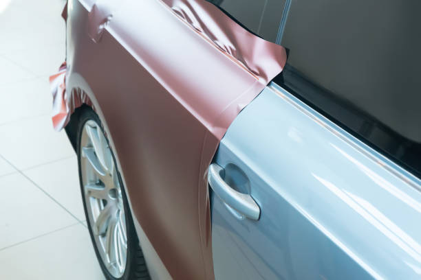 A 4K stock photo showing a red car being prepared for painting inside an auto repair garage. The image captures the process of surface preparation, sanding, and masking, emphasizing precision, craftsmanship, and automotive maintenance — ideal for car service, detailing, and repair themes.