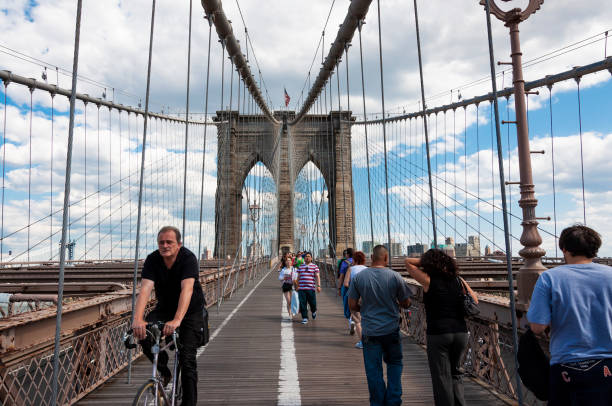 People walking and a cyclist at the Brooklyn Bridge stock photo