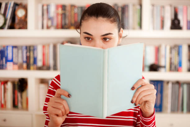 istock beautiful woman reading book at library 1136911316