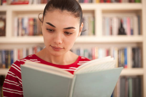 istock beautiful woman reading book at library 1136911376
