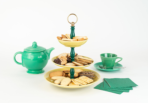 Three Tier  Mid-Century Modern Serving Dish with Yellow Glazed Plates  and Green Bakelite Stem with Brass Ring Handle for Desserts or Appetizers with Tea Pot and Cup, Cookies and Napkins.