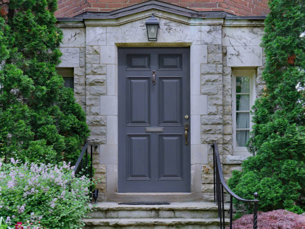 front door of stone faced house surrounded by cedar bushes stock photo