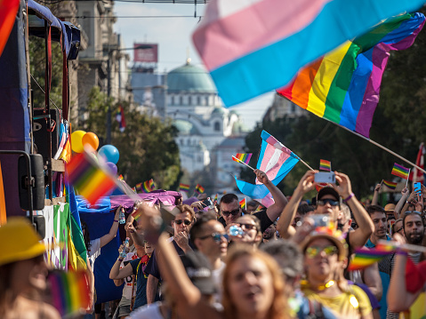 Picture of a crowd of people holding and raising rainbow flags, symbol of the homosexual struggle, and transgender flags during the 2018 edition of the Belgrade gay pride in Serbia. The pride was held on the 16th of September, it was the fourth consecutive edition without clashes, after several years of prohibition, and other years where huge fights opposed demonstrators, policemen and anti-homosexual activists\