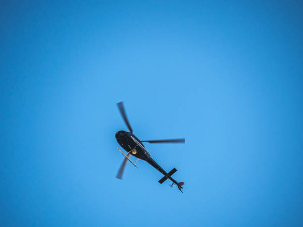 istock A helicopter or chopper hovers overhead on a bright blue sky background. 1136924816