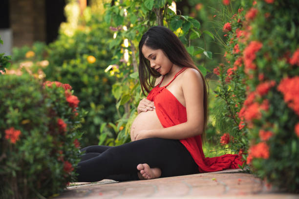 schwangere frau sitzt im garten - mothers day mother single flower family stock-fotos und bilder