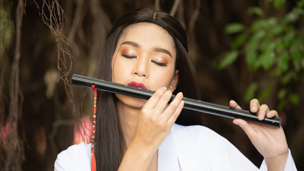 chinese girl is playing the traditional chinese musical instrument; asia young woman play flute in the nature. - plucking an instrument imagens e fotografias de stock